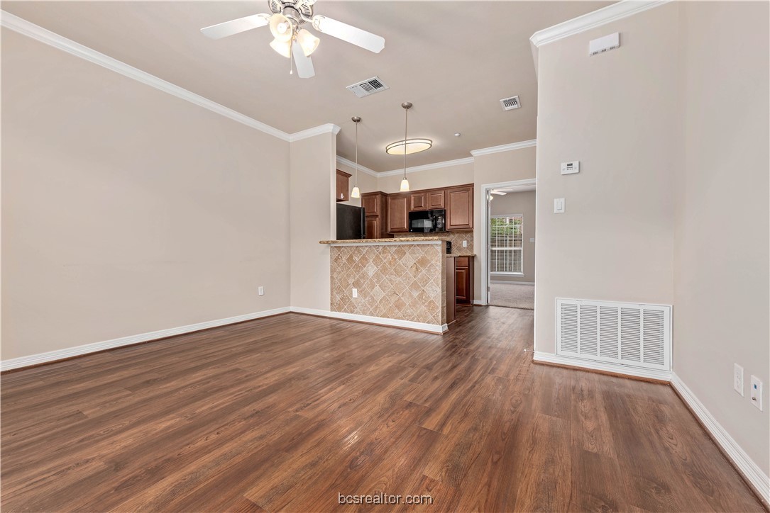 1198 Jones-Butler Road, Unit 2003 College Station, TX 77840 - Photo 4 of 22 Unfurnished living room featuring ceiling fan, dark hardwood / wood-style flooring, and crown molding