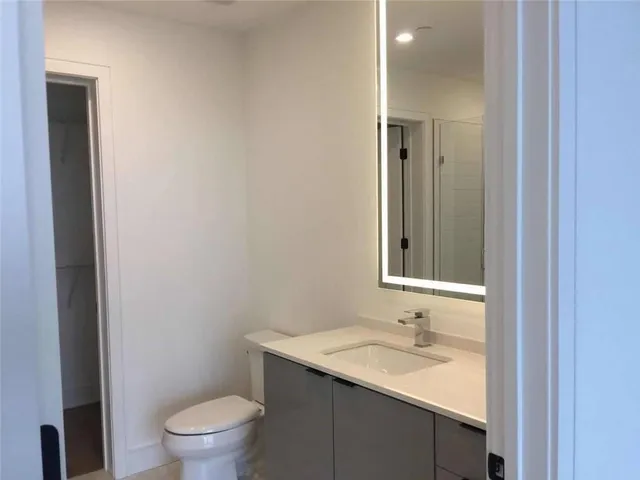 a bathroom with a granite countertop sink toilet and mirror