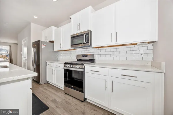 a kitchen with white cabinets and stainless steel appliances
