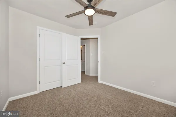 an empty room with closet and a chandelier fan
