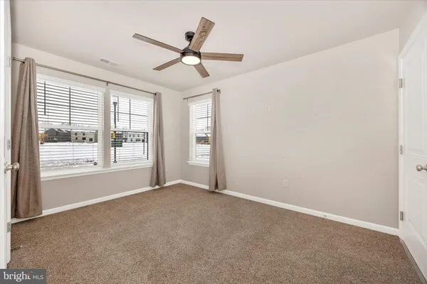 an empty room with windows and fan