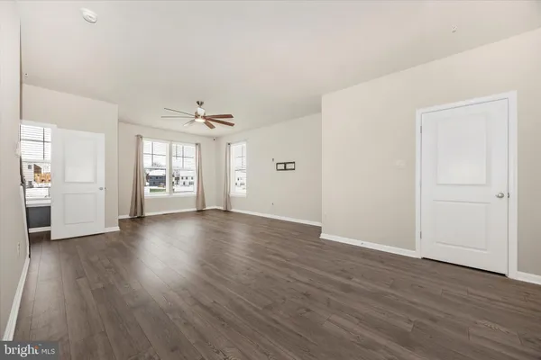 an empty room with wooden floor cabinet and windows