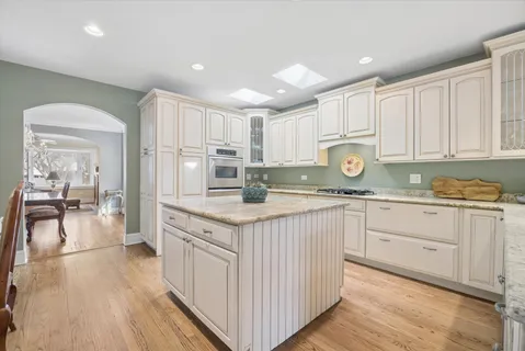 a kitchen with stainless steel appliances granite countertop a stove a sink dishwasher and a refrigerator with wooden floor