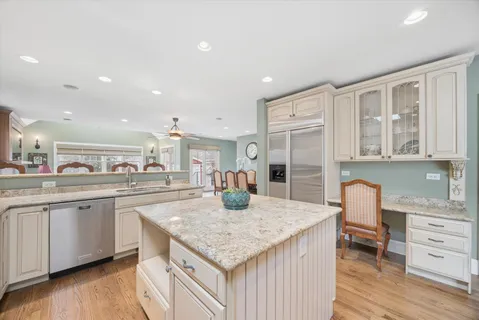 a kitchen with granite countertop kitchen island wooden floor center island and stainless steel appliances