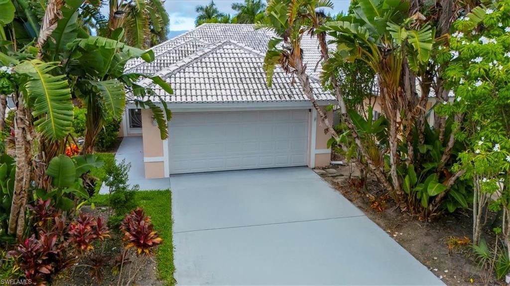 3609 Corinthian Way Naples, FL 34105 - Photo 4 of 23 View of front facade with stucco siding, a tile roof, concrete driveway, and a garage