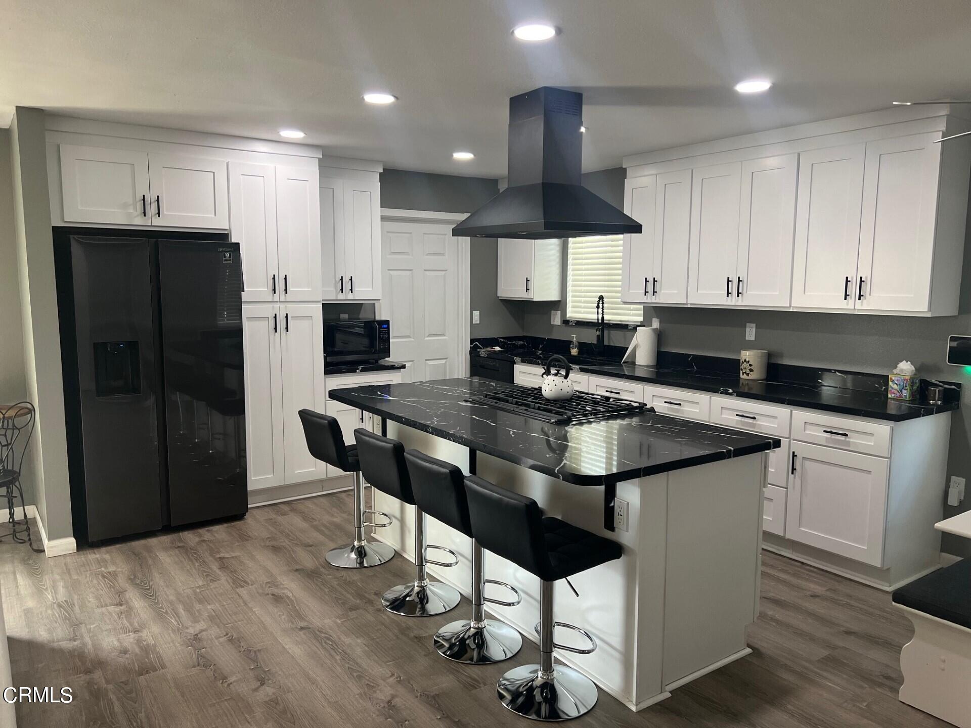 2700 Altus Way Oxnard, CA 93035 - Photo 4 of 10 a kitchen with granite countertop a refrigerator a stove a sink a dining table and chairs