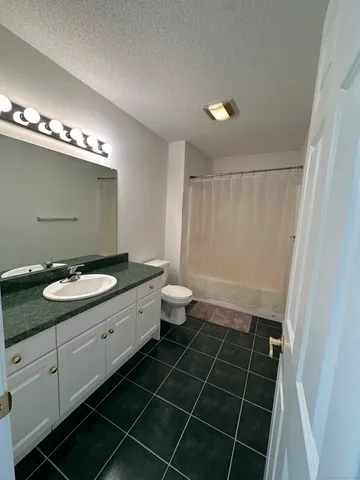 a bathroom with a granite countertop sink a toilet a mirror and shower