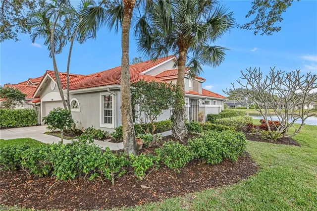 a backyard of a house with potted plants and palm trees