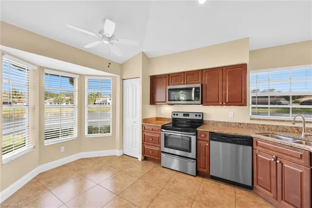 a kitchen with stainless steel appliances granite countertop a stove top oven a sink dishwasher a dining table and chairs with wooden floor