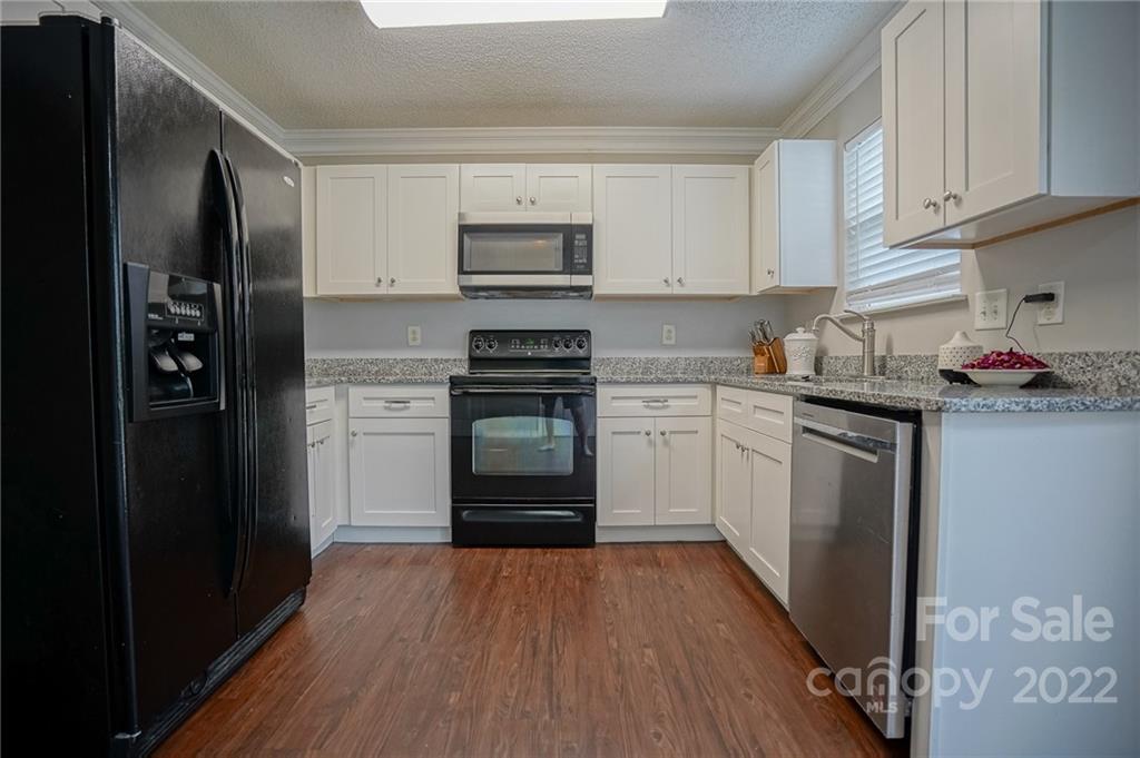 839 Matthews School Road Matthews, NC 28105 - Photo 11 of 37 a kitchen with stainless steel appliances granite countertop a refrigerator a sink dishwasher and white cabinets with wooden floor