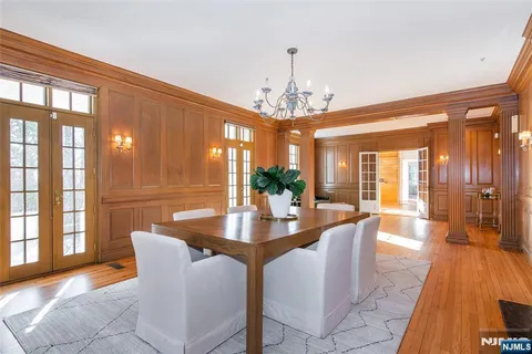 a dining room with wooden floor a chandelier a wooden table and chairs