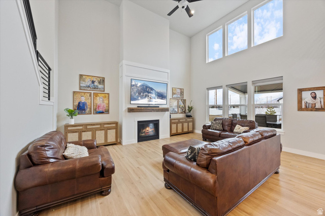 754 West 400 North, Unit 29 Mapleton, UT 84664 - Photo 5 of 25 Living area featuring a glass covered fireplace, light wood finished floors, ceiling fan, and a high ceiling