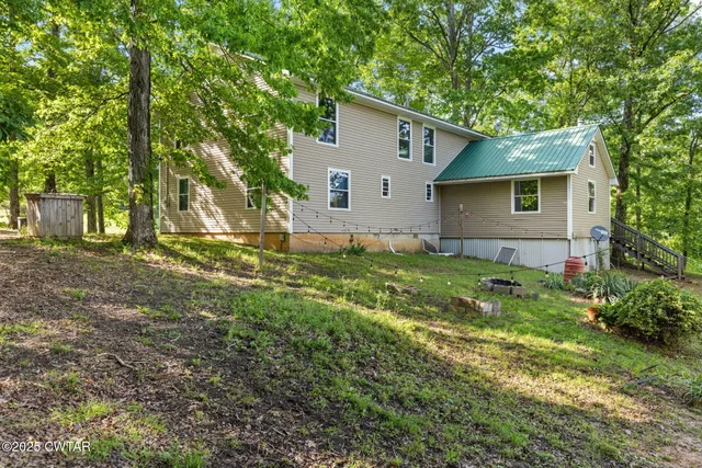 a backyard of a house with plants and large tree