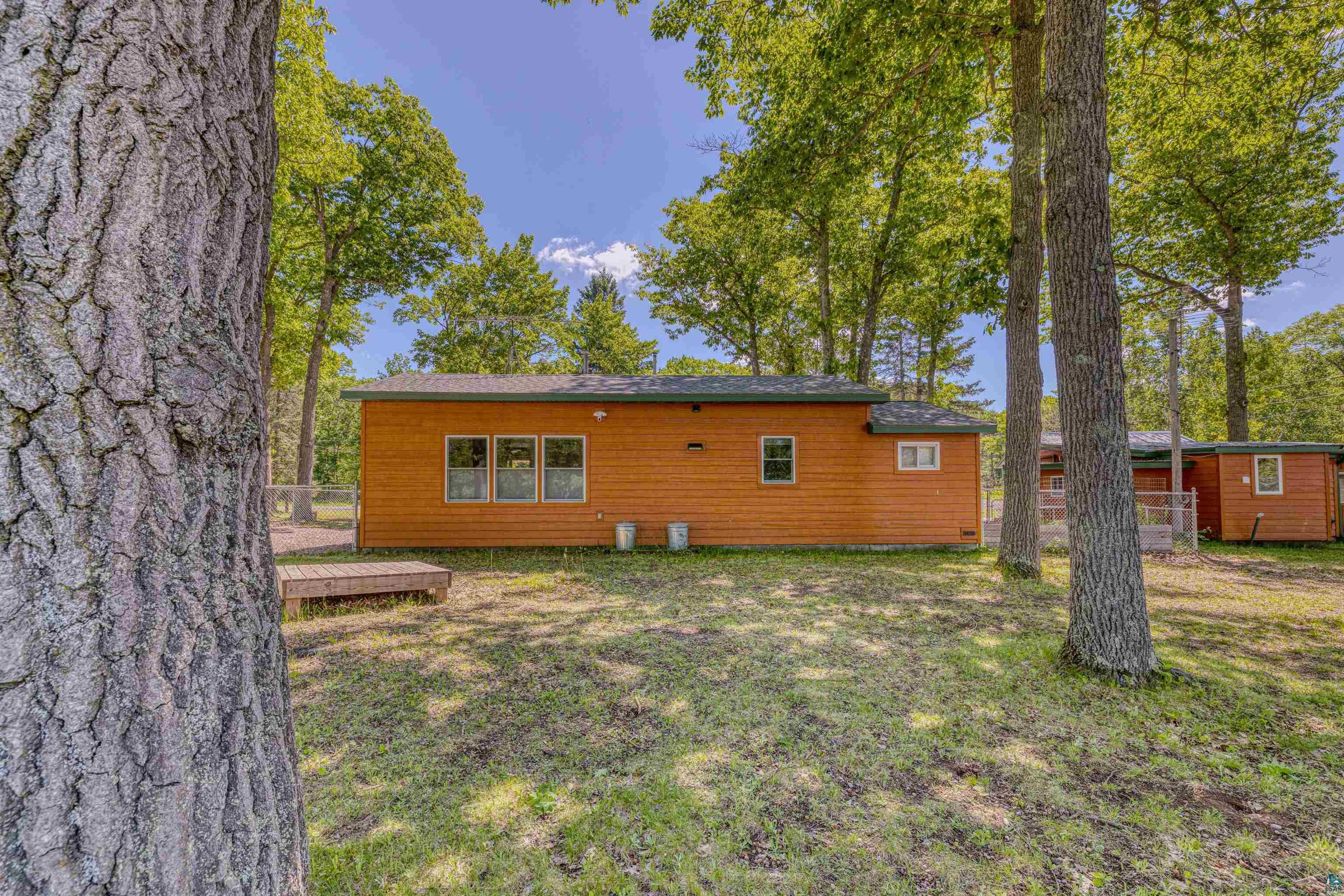 66075 Rooster Road Iron River, WI 54847 - Photo 45 of 52 Wood-sided cabin with a dark roof and multiple windows, surrounded by mature trees