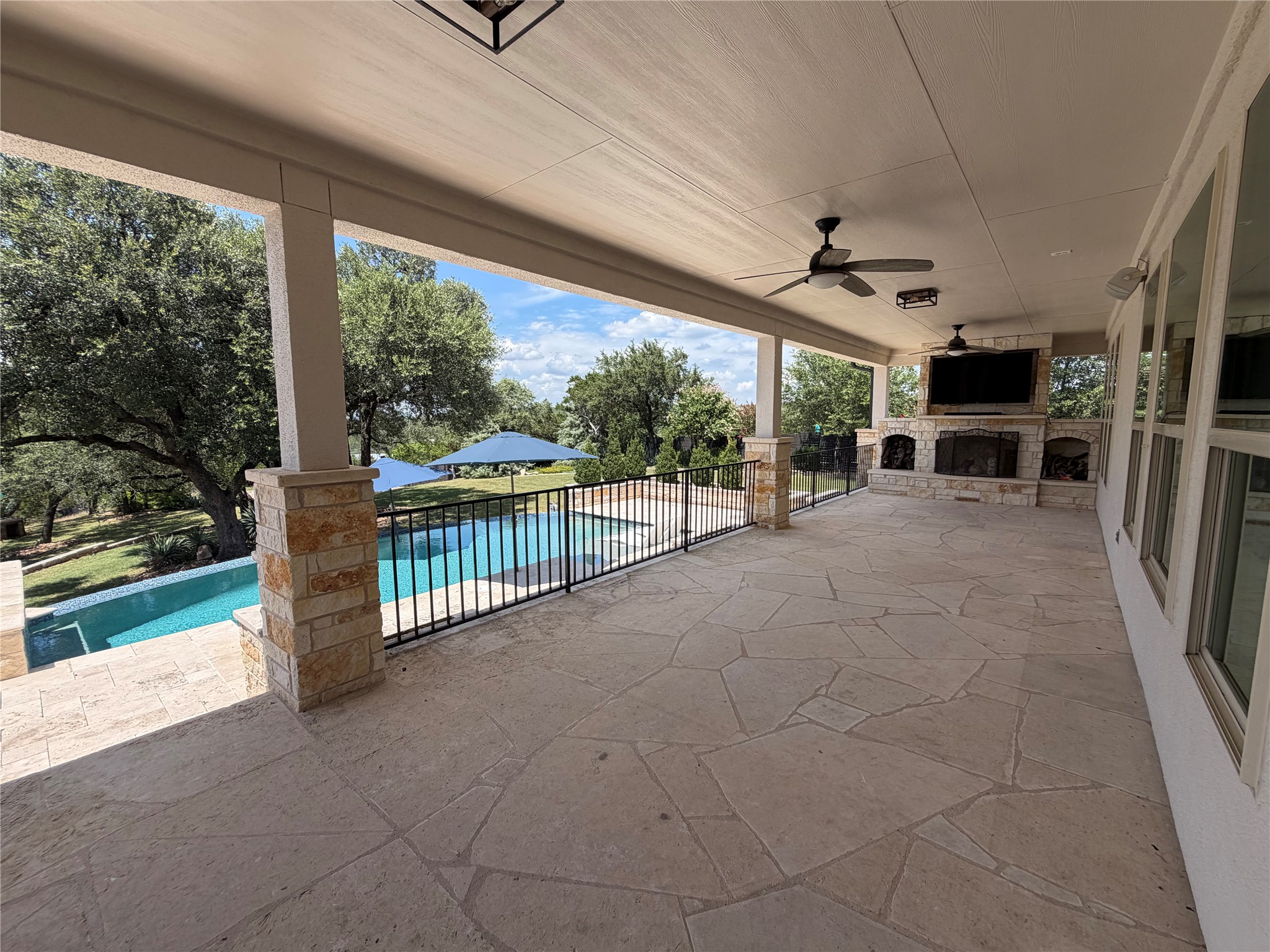7801 Aria Loop Austin, TX 78736 - Photo 17 of 40 Picturesque Covered Patio with outdoor fireplace spans the back of the house and includes plenty of spaces for grilling and hanging out