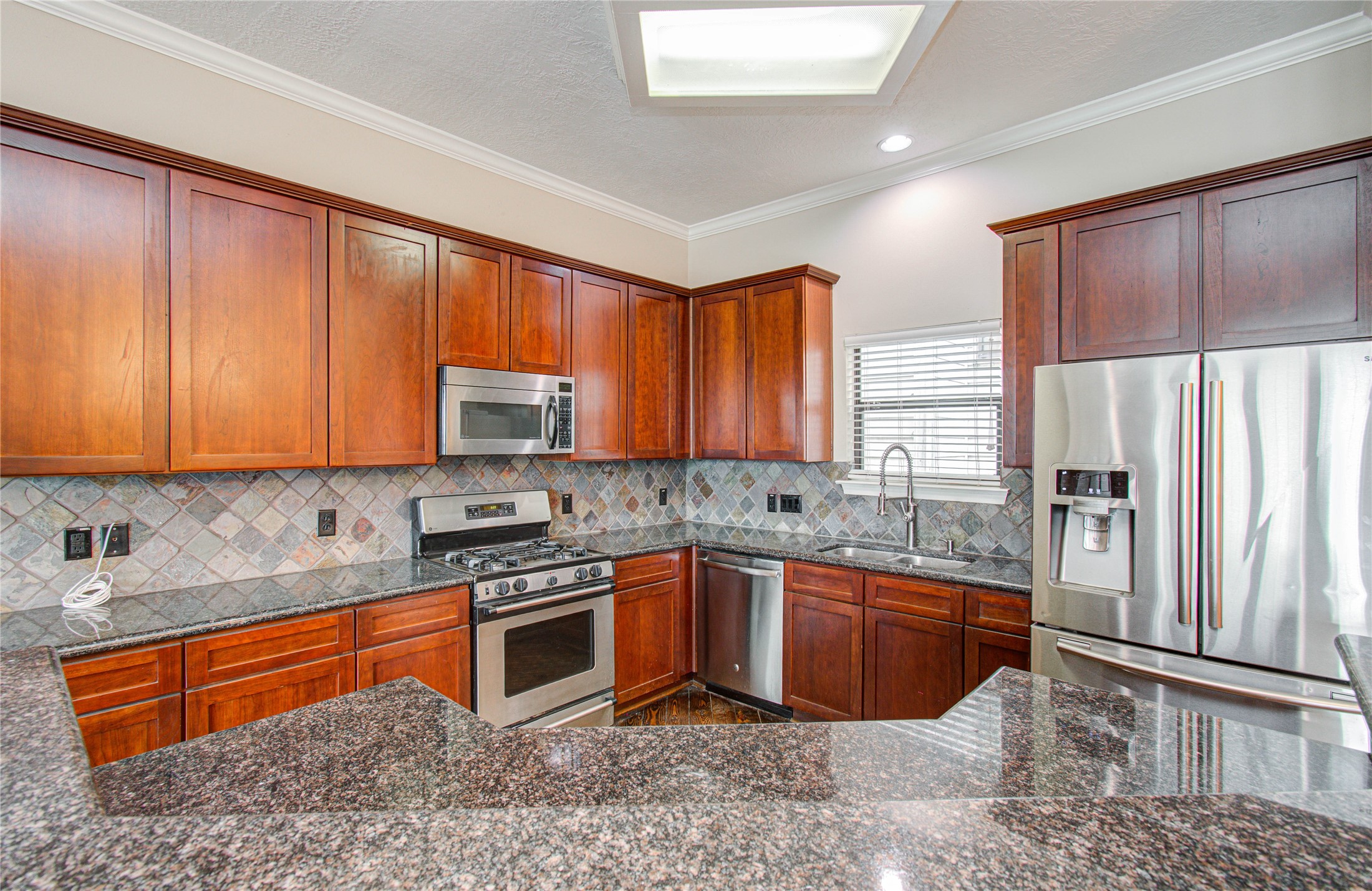 2304 Jackson Street Houston, TX 77004 - Photo 13 of 31 Kitchen features rich wood cabinetry with ample storage, stainless steel appliances, granite countertops, and tile backsplash.