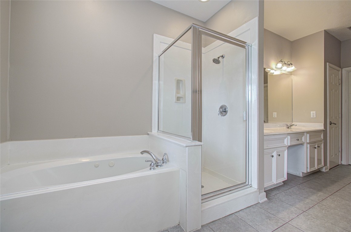 2304 Jackson Street Houston, TX 77004 - Photo 23 of 31 Primary bathroom with a large bathtub, glass-enclosed shower, dual-sink vanity, and neutral tile flooring.