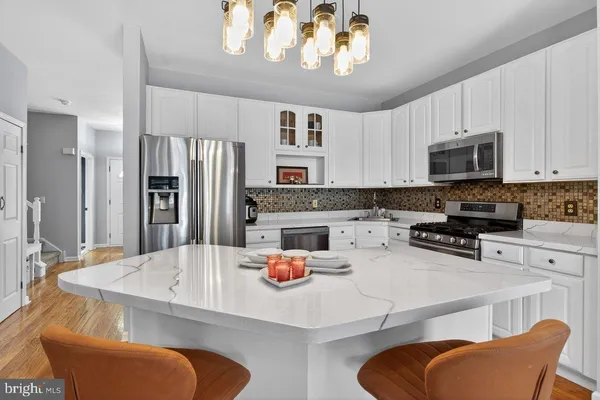 a kitchen with stainless steel appliances kitchen island granite countertop a dining table and chairs in it