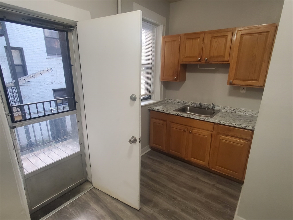 76 Walnut Park, Unit 1 Boston, MA 02119 - Photo 2 of 12 a kitchen with a sink a refrigerator and cabinets