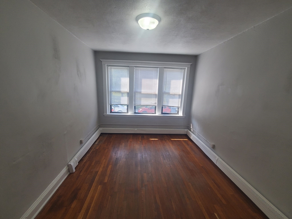 76 Walnut Park, Unit 1 Boston, MA 02119 - Photo 4 of 12 wooden floor in an empty room with a window