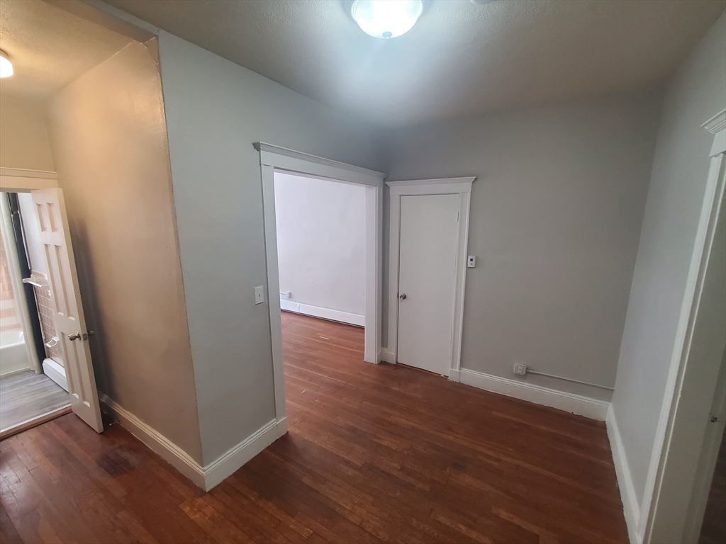 76 Walnut Park, Unit 1 Boston, MA 02119 - Photo 10 of 12 an empty room with wooden floor and entrance
