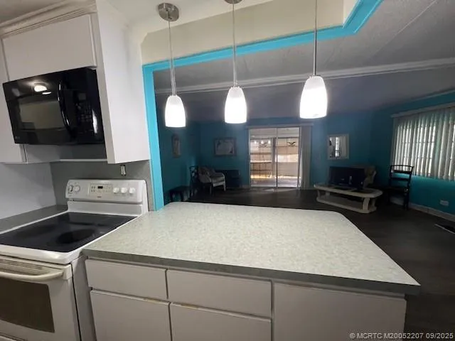 a kitchen with a stove a sink and a flat screen tv