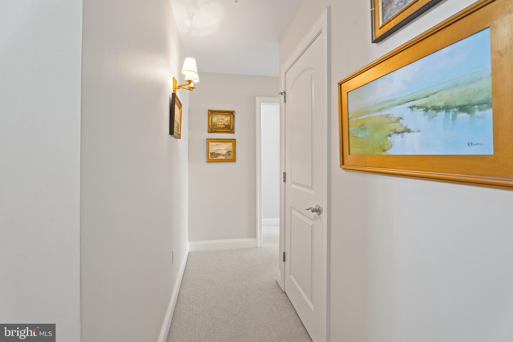 37304 Lighthouse Road, Unit 10 Selbyville, DE 19975 - Photo 27 of 40 a view of a hallway with paintings on the wall