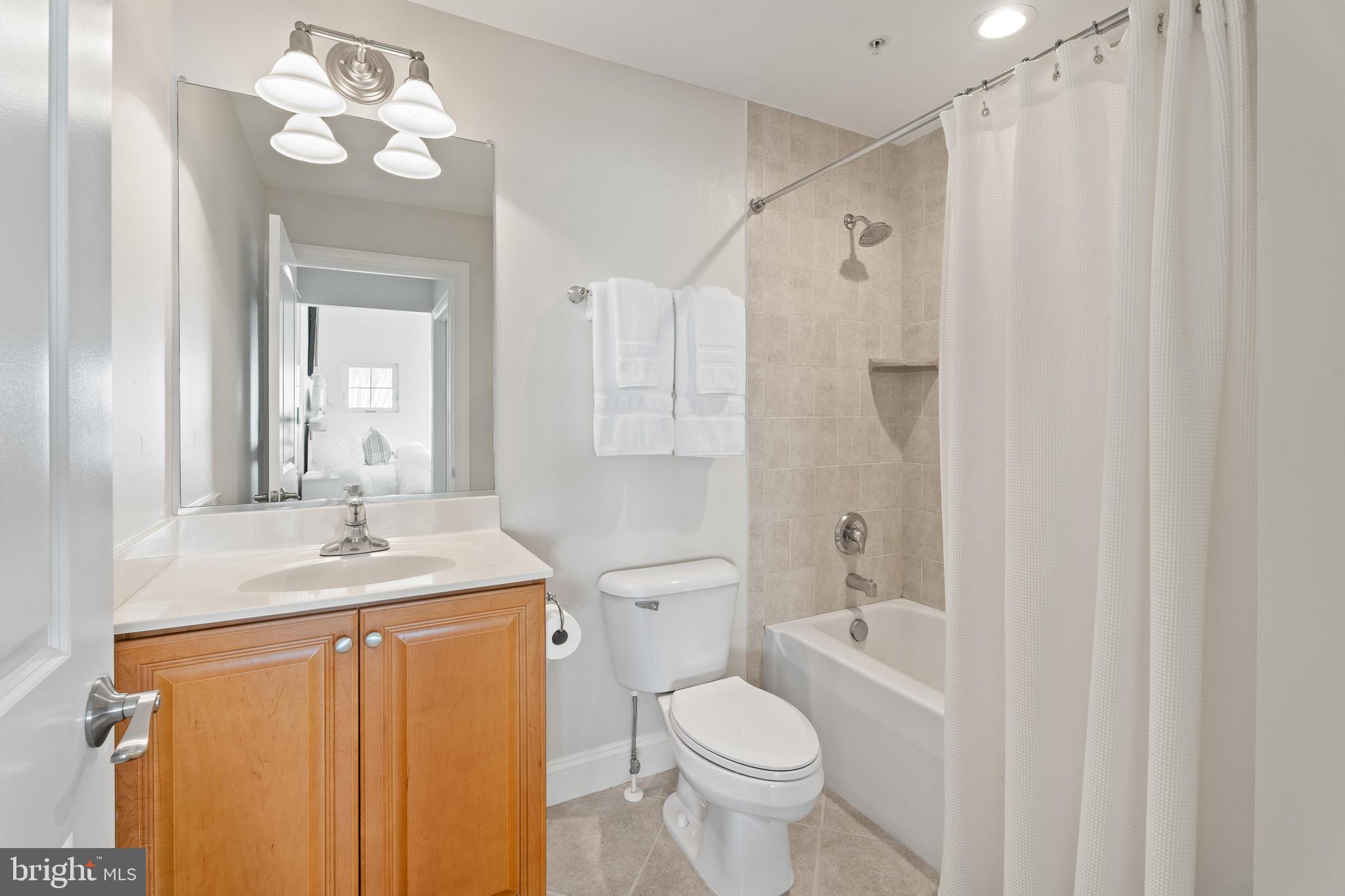 37304 Lighthouse Road, Unit 10 Selbyville, DE 19975 - Photo 38 of 40 a bathroom with a granite countertop sink toilet a mirror a vanity and shower