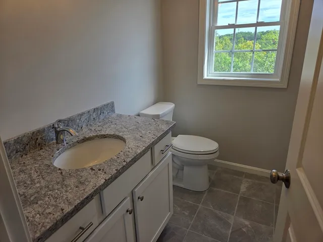 a bathroom with a granite countertop sink toilet and a mirror