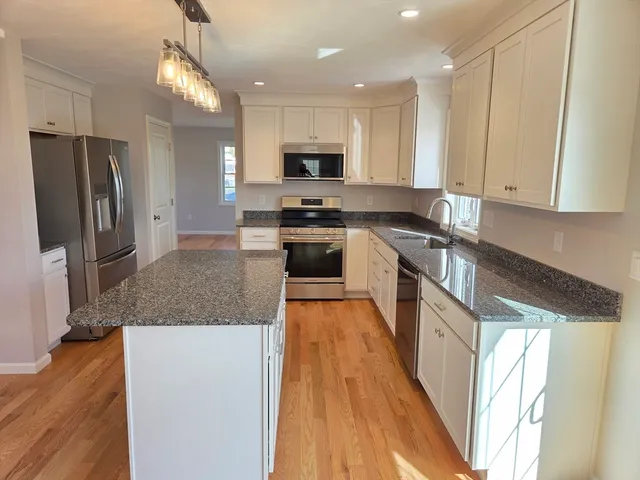a large kitchen with stainless steel appliances granite countertop a stove a sink and a refrigerator
