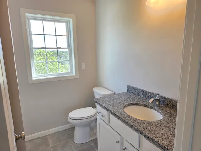 a bathroom with a granite countertop sink a toilet and a window