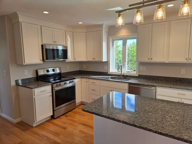 a kitchen with granite countertop a sink a counter top space appliances and cabinets