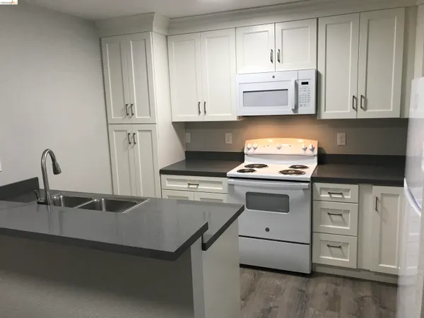 a kitchen with granite countertop white cabinets and white appliances