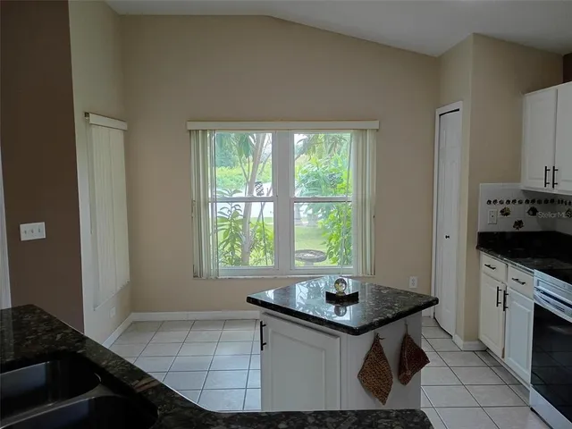 a kitchen with granite countertop a sink stove and cabinets
