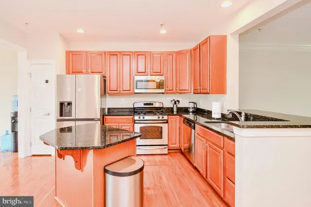 a kitchen with stainless steel appliances granite countertop a refrigerator a stove and a sink