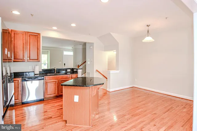 a view of a kitchen with kitchen island a sink wooden floor and a living room