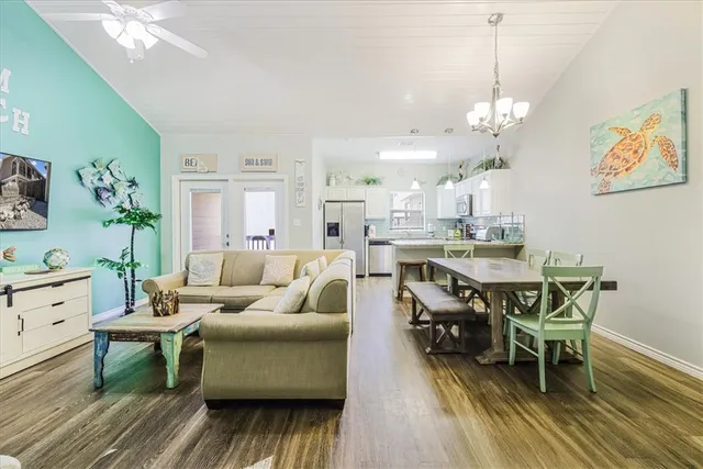 a living room with furniture kitchen view and a chandelier