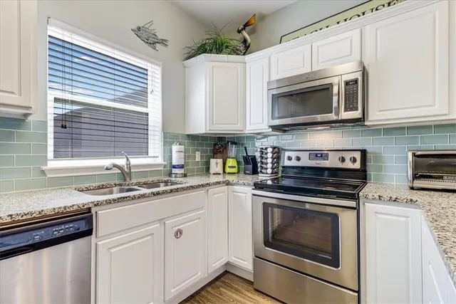 a kitchen with white cabinets and appliances