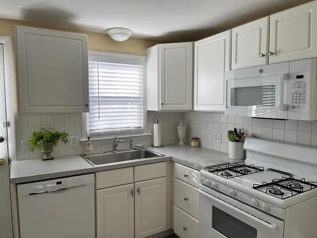 a kitchen with granite countertop a sink stove and white cabinets