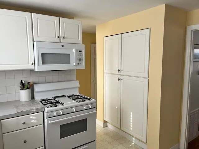 a kitchen with stainless steel appliances white cabinets and a stove top oven