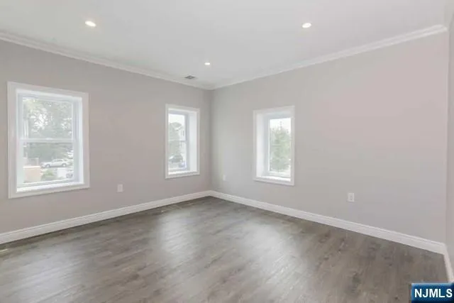 a view of an empty room with wooden floor and window