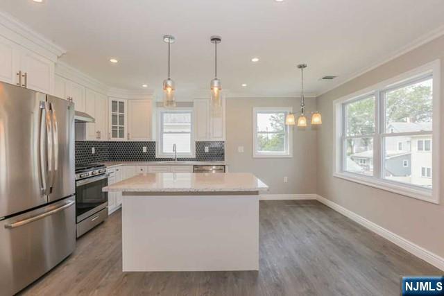 24 Henry Place, Unit 2 Hackensack, NJ 07601 - Photo 9 of 26 a kitchen with kitchen island white cabinets and stainless steel appliances