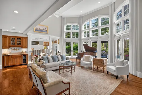 a living room with furniture large window and wooden floor