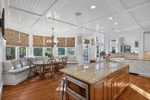 a dining hall with stainless steel appliances granite countertop a table and chairs
