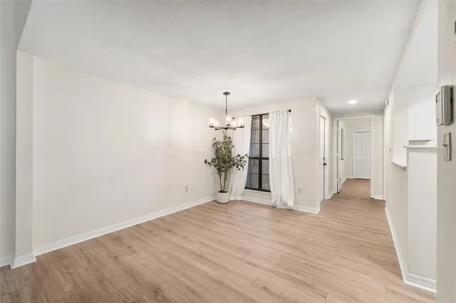 a view of a hallway with wooden floor and a refrigerator