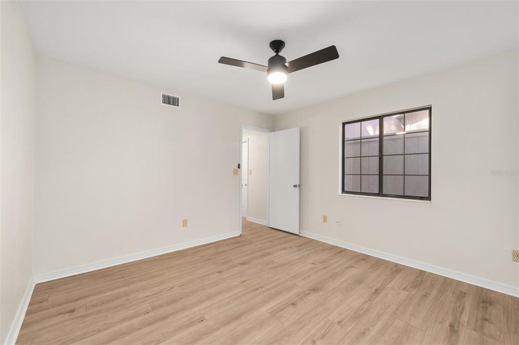 912 Southwest 57th Drive Gainesville, FL 32607 - Photo 16 of 34 an empty room with wooden floor chandelier fan and windows