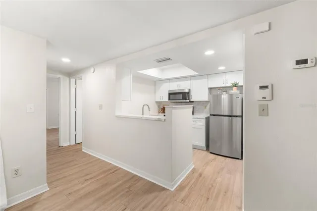 a view of a kitchen with refrigerator and wooden floor