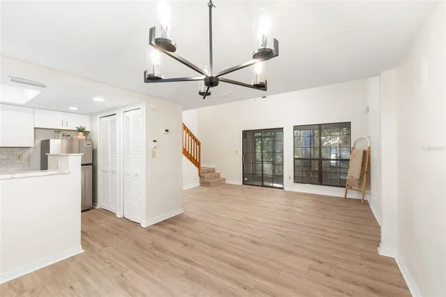 a view of an empty room with wooden floor and a kitchen