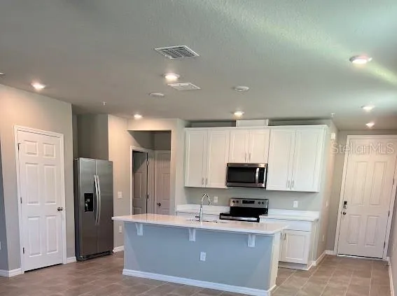a kitchen with stainless steel appliances granite countertop a refrigerator and a stove top oven