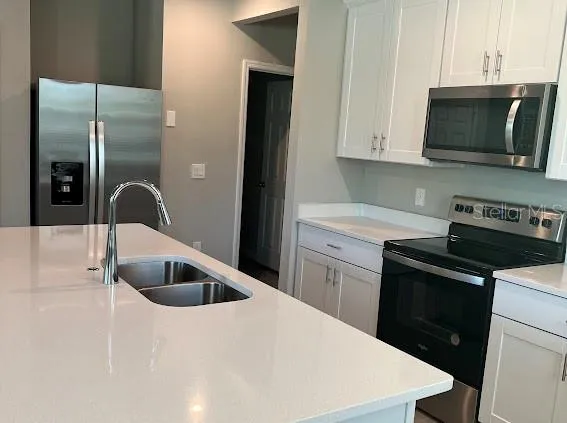 a kitchen with a sink and a stove top oven with wooden floor